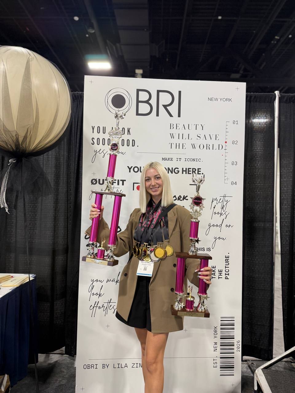 Kristina Strilets with a trophy at a professional beauty event